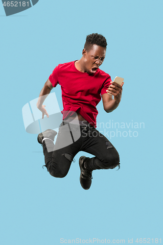 Image of always on mobile. Full length of handsome young man taking phone while jumping