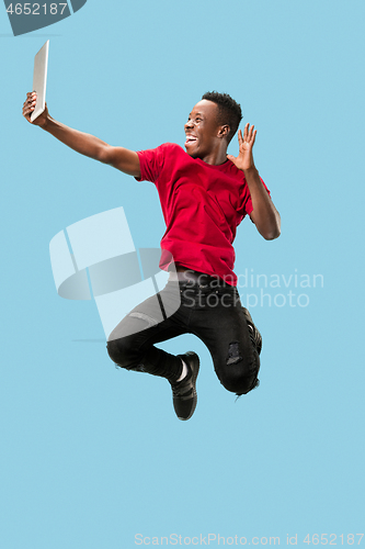 Image of Image of happy excited young african man jumping isolated over yellow background using laptop