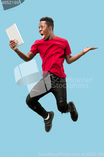 Image of Image of happy excited young african man jumping isolated over yellow background using laptop