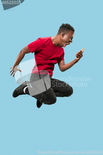 Image of always on mobile. Full length of handsome young man taking phone while jumping