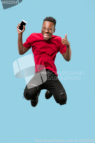 Image of always on mobile. Full length of handsome young man taking phone while jumping