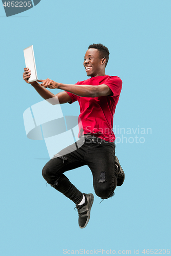 Image of Image of happy excited young african man jumping isolated over yellow background using laptop