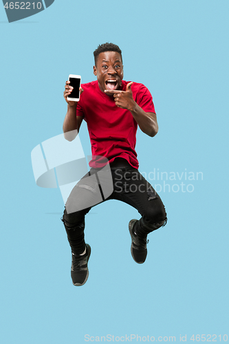 Image of always on mobile. Full length of handsome young man taking phone while jumping