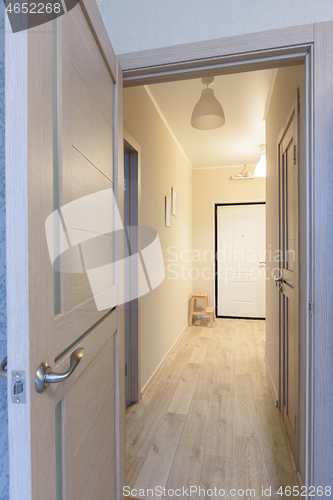 Image of Interior door in the foreground, then the passage from the room to the hallway in a one-room small apartment