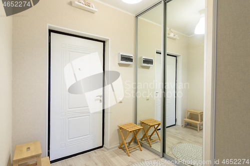 Image of Entrance hall interior with metal front door and large sliding wardrobe with mirrors