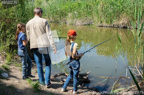 Image of Dad with two daughters fishing on a lake