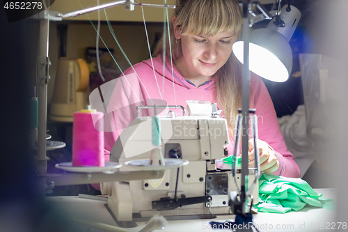 Image of Girl works by light lamp behind industrial sewing machine