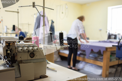 Image of sewing equipment in the workshop and seamstress in the background