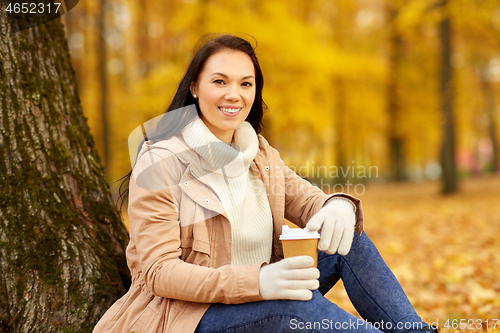 Image of woman drinking takeaway coffee in autumn park