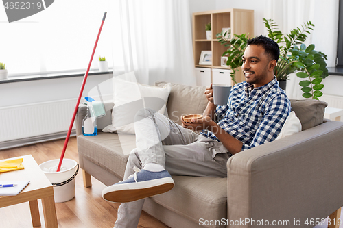 Image of man drinking coffee, resting after home cleaning