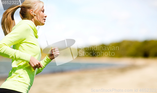 Image of woman with earphones running at park