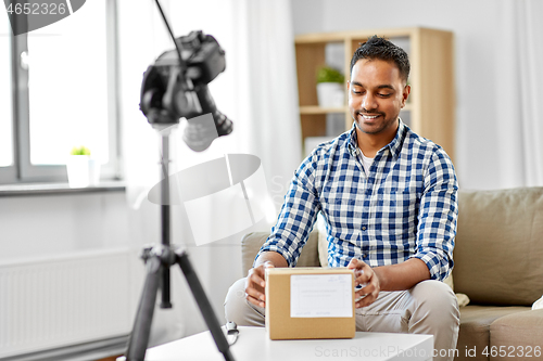 Image of male video blogger opening parcel box at home