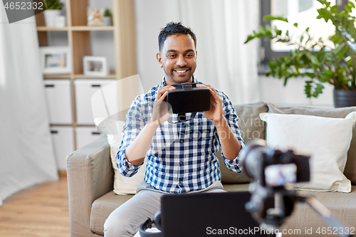 Image of male blogger with vr glasses videoblogging at home