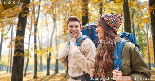 Image of smiling couple with backpacks hiking in autumn