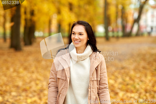 Image of beautiful happy young woman smiling in autumn park