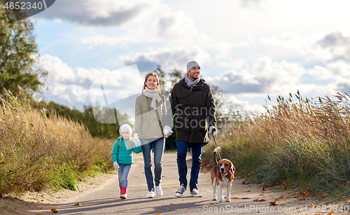 Image of happy family walking with beagle dog in autumn