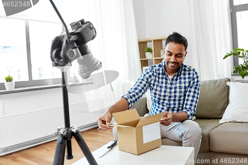 Image of male video blogger opening parcel box at home