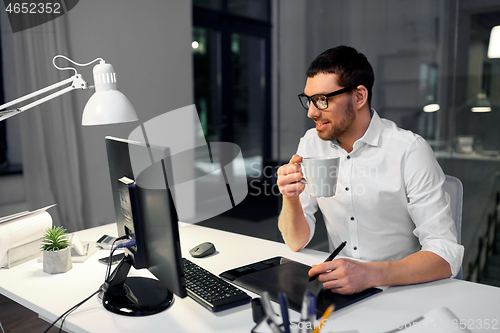 Image of designer with pen tablet drinking coffee at office