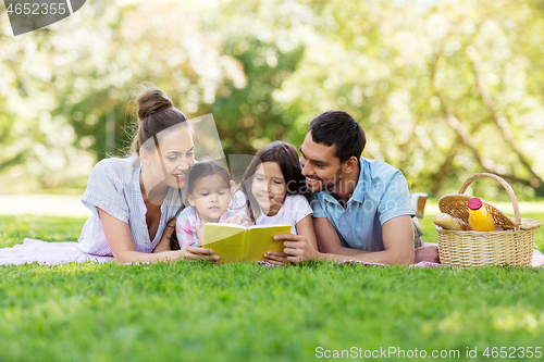 Image of family reading book on picnic in summer park