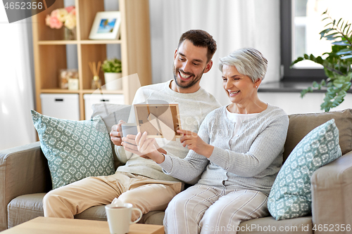 Image of adult son and senior mother with photo at home