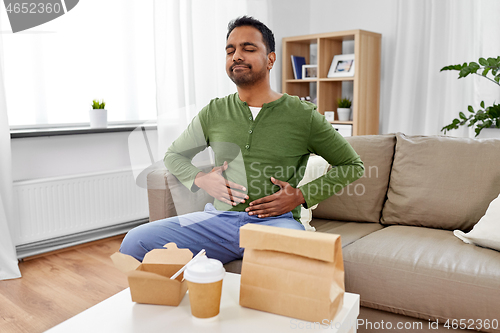 Image of pleased indian man eating takeaway food at home