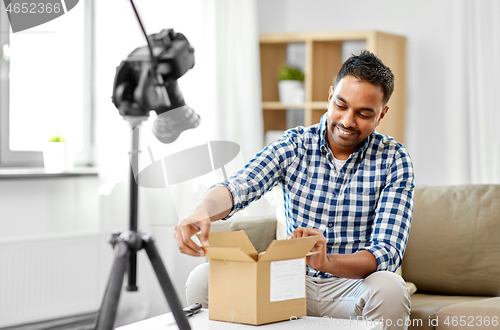 Image of male video blogger opening parcel box at home