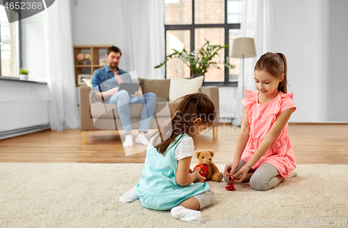 Image of girls playing with toy crockery and teddy at home