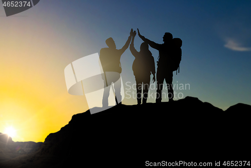 Image of travelers making high five over sunrise