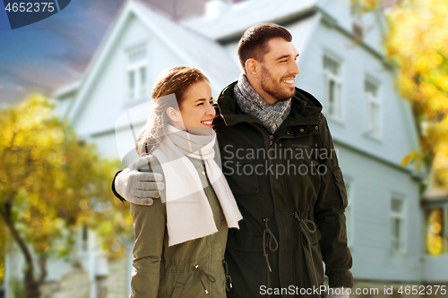 Image of smiling couple hugging over house in autumn