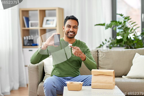 Image of indian man using smartphone for food delivery