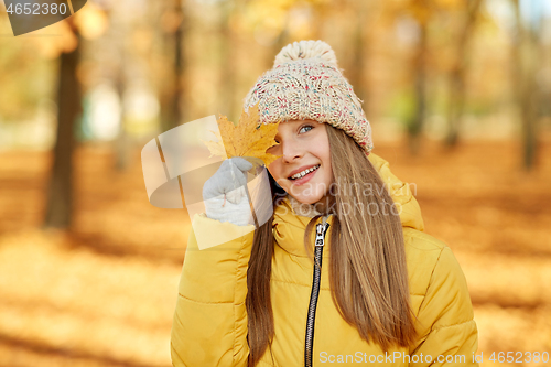 Image of portrait of girl with maple leaf at autumn park