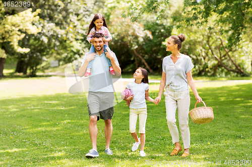 Image of family with picnic basket walking in summer park