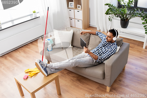 Image of indian man in headphones after cleaning home