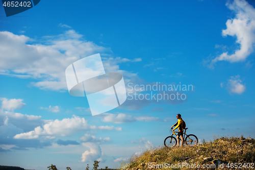 Image of Cyclist riding a bike on off road to the sunset