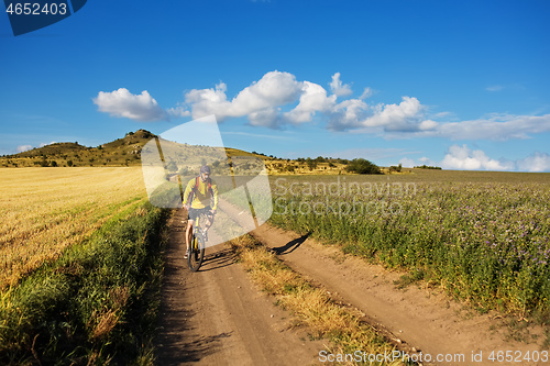 Image of Cyclist riding a bike on off road to the sunset