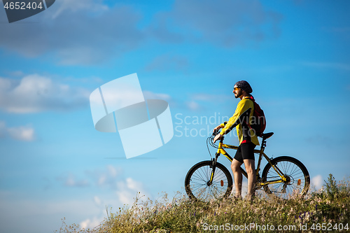 Image of Cyclist riding a bike on off road to the sunset