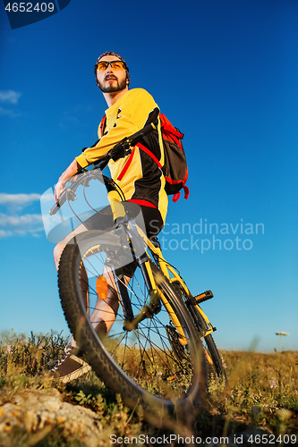 Image of Cyclist man standing on top of a mountain with bicycle