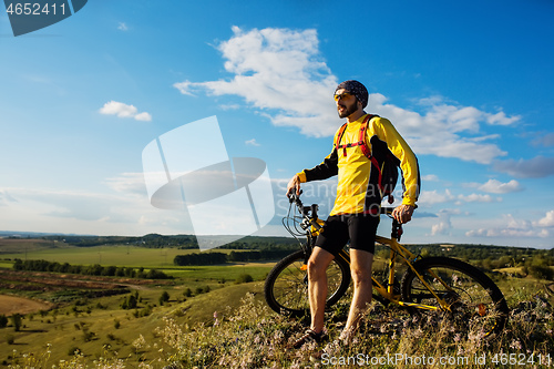 Image of Cyclist riding a bike on off road to the sunset