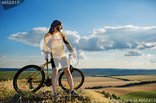 Image of Cyclist riding a bike on off road to the sunset