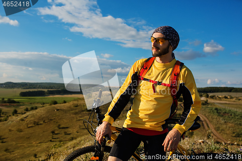 Image of Cyclist riding a bike on off road to the sunset