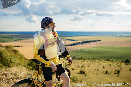 Image of Cyclist riding a bike on off road to the sunset