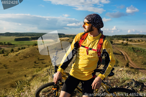 Image of Cyclist riding a bike on off road to the sunset