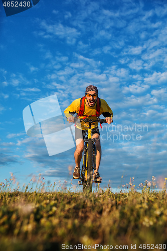 Image of Cyclist man standing on top of a mountain with bicycle