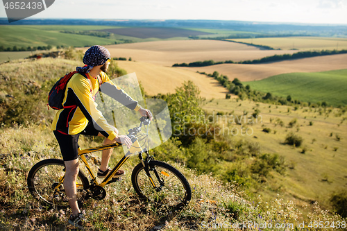 Image of Cyclist riding a bike on off road to the sunset