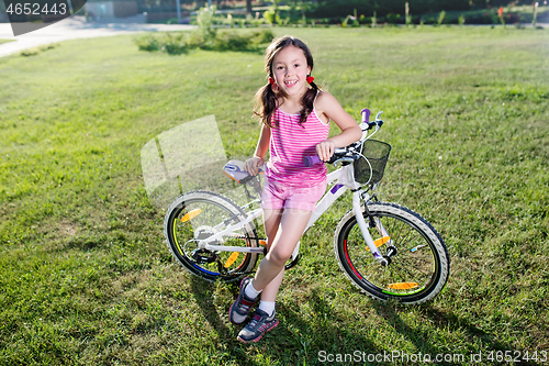 Image of Portrait of funny girl in pink clothes on her bike