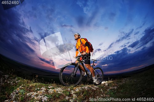 Image of Man in helmet stay on bicycle under sky with clouds.