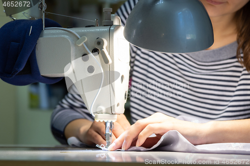 Image of close-up of the hands of a girl working on a sewing machine