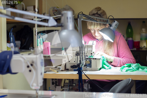 Image of garment worker at the work desk by the light of the lamp