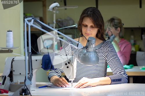 Image of a seamstress works behind a sewing machine in a sewing shop at her workplace