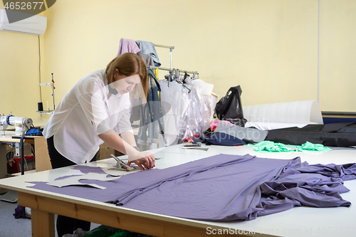 Image of Fashion designer cuts on the material details of clothes in the 